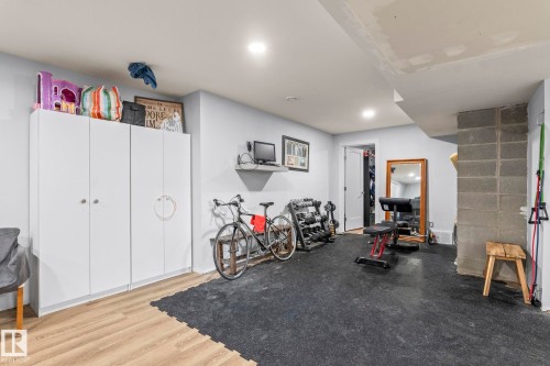 Open recreation room featuring light wood-finish flooring, recessed lighting, and built-in white cabinetry providing ample storage - 23133 Twp Rd 502, Rural Leduc County, AB - Indoor
