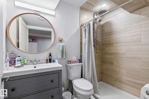 Bathroom featuring a contemporary vanity with an integrated sink, a large circular mirror with a wood-finish frame, and modern wall-mounted lighting - 23133 Twp Rd 502, Rural Leduc County, AB - Indoor Photo Showing Bathroom