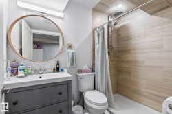 Bathroom featuring a contemporary vanity with an integrated sink, a large circular mirror with a wood-finish frame, and modern wall-mounted lighting - 