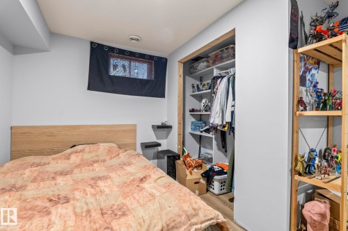 Bedroom featuring light-toned walls, wood-finish headboard, a built-in closet with shelving and hanging space, a small window, and floating wall shelves - 23133 Twp Rd 502, Rural Leduc County, AB - Indoor Photo Showing Bedroom