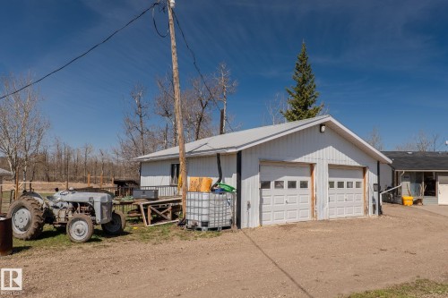 Detached garage with two white overhead doors and a white metal roof - 23133 Twp Rd 502, Rural Leduc County, AB - Outdoor