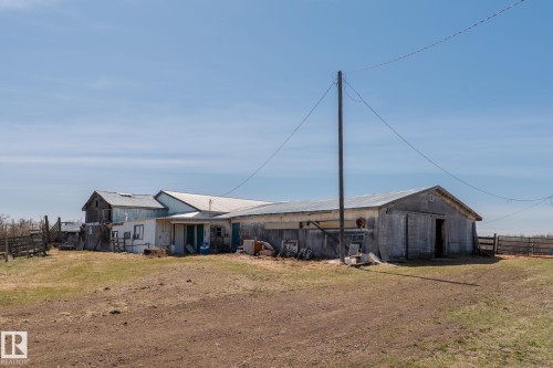 Rural property featuring multiple outbuildings, corrugated metal roofing, and a wooden fence line - 23133 Twp Rd 502, Rural Leduc County, AB - Outdoor