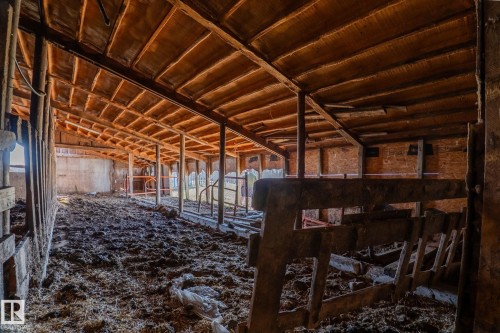 Exposed wood beam ceiling structure with a sloped roofline, wood plank walls, and concrete flooring - 23133 Twp Rd 502, Rural Leduc County, AB - Indoor