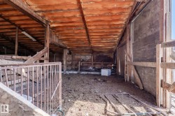 Expansive barn interior featuring exposed wood beam construction, a concrete floor, and natural light - 