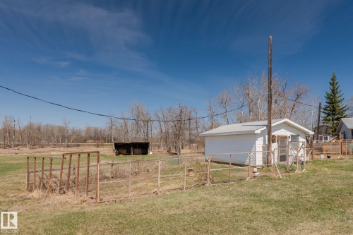 White outbuilding with a metal roof, fenced enclosure, and surrounding green space - 23133 Twp Rd 502, Rural Leduc County, AB - Outdoor