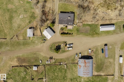 Rural property featuring a main residence with a dark shingle roof, accompanied by multiple outbuildings, open fields, and a large metal Quonset hut - 23133 Twp Rd 502, Rural Leduc County, AB - Outdoor With View
