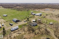 Expansive rural property featuring a primary residence, multiple outbuildings, open fields, and wooded areas - 