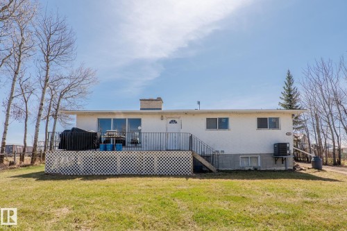 White stucco exterior with a large rear deck featuring lattice skirting - 23133 Twp Rd 502, Rural Leduc County, AB - Outdoor With Deck Patio Veranda