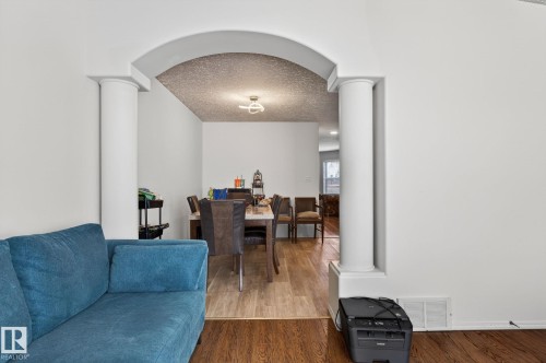 Archway opening with decorative columns, leading to a dining area featuring wood-finish flooring - 4603 126 Avenue, Edmonton, AB - Indoor Photo Showing Living Room
