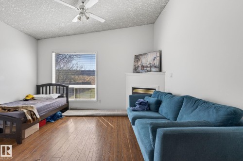 Room featuring wood-finish flooring, a prominent window, white walls, and a ceiling fan - 4603 126 Avenue, Edmonton, AB - Indoor Photo Showing Bedroom