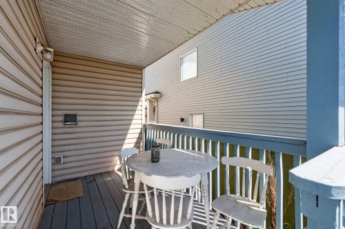 Covered outdoor patio area featuring a slatted ceiling, wood-finish flooring, and a blue-painted railing - 4603 126 Avenue, Edmonton, AB - Outdoor With Deck Patio Veranda With Exterior