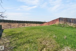 Expansive grassy area with a partial privacy fence - 