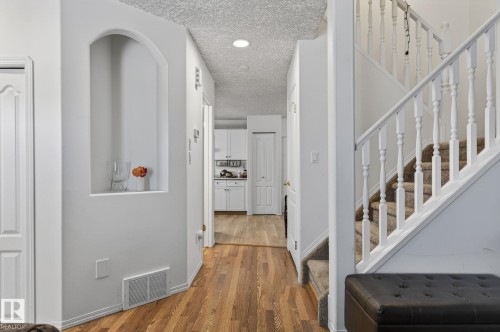 Arch wall niche with hardwood flooring and carpeted staircase featuring white balusters - 4603 126 Avenue, Edmonton, AB - Indoor Photo Showing Other Room
