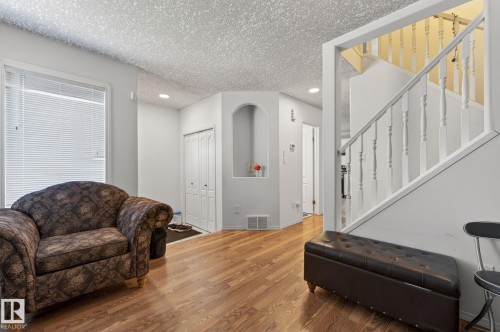 Open living space featuring wood-finish flooring, a contemporary staircase with white balusters, and recessed ceiling lighting - 4603 126 Avenue, Edmonton, AB - Indoor