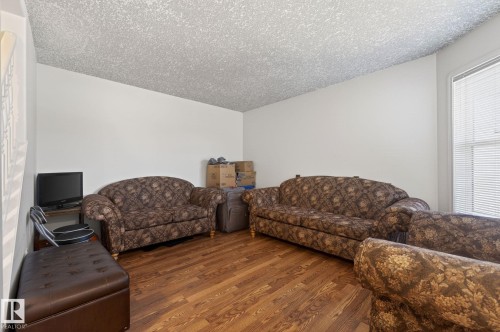 Spacious room featuring wood-finish flooring, white painted walls, and a textured ceiling - 4603 126 Avenue, Edmonton, AB - Indoor Photo Showing Living Room