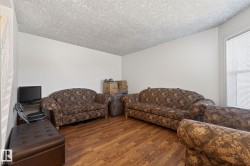 Spacious room featuring wood-finish flooring, white painted walls, and a textured ceiling - 