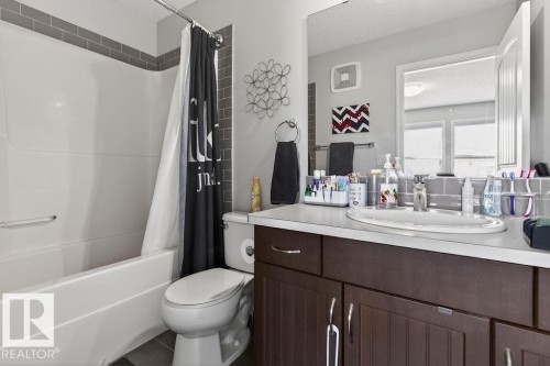 Bathroom featuring a white bathtub, subway tile surround, dark wood-finish vanity with a light countertop, and a built-in mirror - 17540 58 Street Nw, Edmonton, AB 