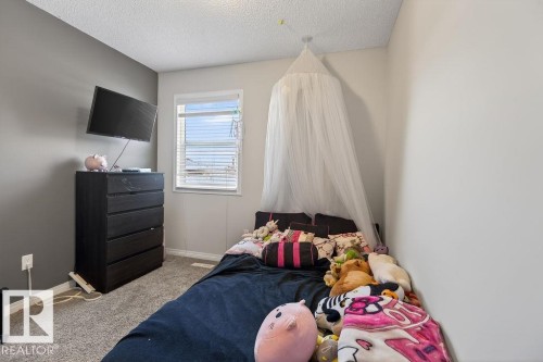 Carpeted room featuring a single window with horizontal blinds, a textured ceiling, and a paneled accent wall - 17540 58 Street Nw, Edmonton, AB 