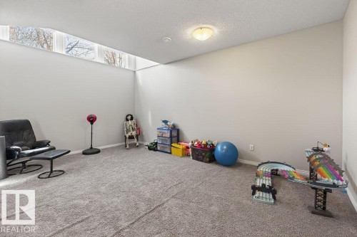 Spacious room featuring high-set transom windows, neutral wall tones, and plush carpeting - 17540 58 Street Nw, Edmonton, AB 