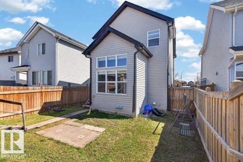 Rear exterior featuring an extended sunroom with large windows, vinyl siding, and a gabled roofline - 17540 58 Street Nw, Edmonton, AB 