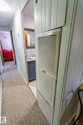 Hallway featuring textured carpet, vertical paneled walls, and a built-in heating unit - 331 60417 Range Road 124, Rural St. Paul County, AB 