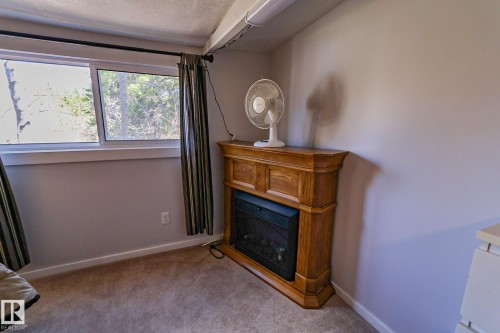 Wood-finish fireplace surround with an electric insert, set against a light-toned wall - 331 60417 Range Road 124, Rural St. Paul County, AB 