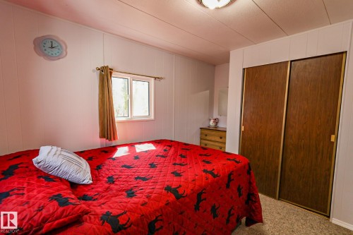 Bedroom featuring light-toned paneling, a single window, and textured carpeting - 331 60417 Range Road 124, Rural St. Paul County, AB 