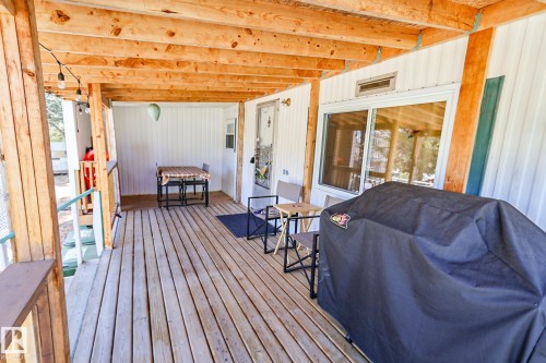 Expansive covered deck featuring natural wood flooring and exposed wood ceiling beams - 331 60417 Range Road 124, Rural St. Paul County, AB 