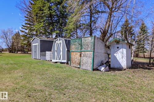 Two storage sheds with dark grey siding and white trim, alongside a smaller white utility building with a green roof accent - 331 60417 Range Road 124, Rural St. Paul County, AB 