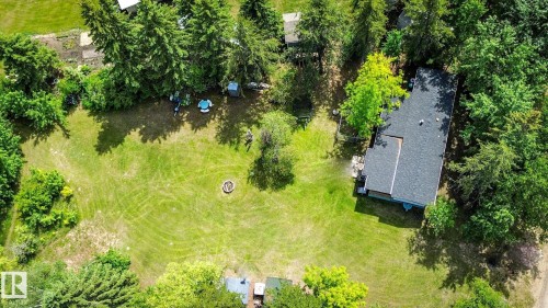 Expansive green lawn surrounded by mature trees, featuring a fire pit - 331 60417 Range Road 124, Rural St. Paul County, AB 