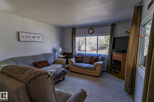 Living area featuring carpet flooring, horizontal wall paneling, and large windows - 331 60417 Range Road 124, Rural St. Paul County, AB 