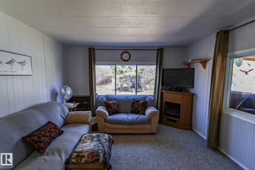 Living area featuring a large picture window, light gray carpeting, and paneled walls - 331 60417 Range Road 124, Rural St. Paul County, AB 