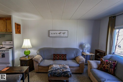 Living area featuring a spacious layout, light-toned paneling, and a visible window with outdoor scenery - 331 60417 Range Road 124, Rural St. Paul County, AB 