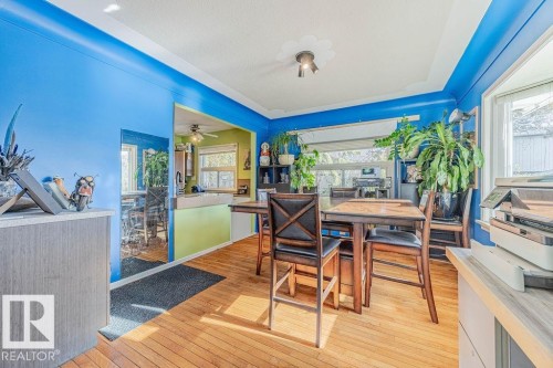 Hardwood flooring throughout featuring a bay window, a built-in archway, and a ceiling light fixture - 12339 89 Street, Edmonton, AB - Indoor Photo Showing Dining Room
