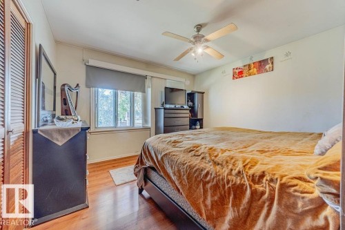 Room featuring wood-finish flooring, wood-paneled walls and ceiling, a recessed fluorescent light fixture, a window with horizontal blinds, and built-in wall shelving - 12339 89 Street, Edmonton, AB - Indoor Photo Showing Bedroom