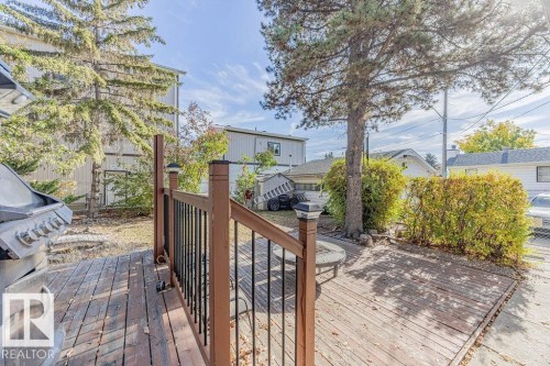 Private backyard featuring a wooden deck, a ground-level wooden patio, and a grassy lawn framed by mature trees - 12339 89 Street, Edmonton, AB - Outdoor