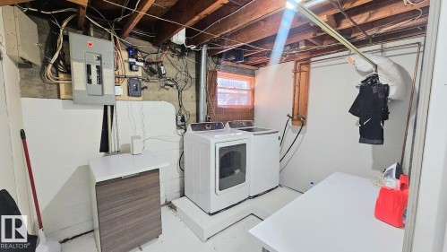 Laundry area featuring an exposed beam ceiling, concrete foundation, and a small casement window - 12339 89 Street, Edmonton, AB - Indoor Photo Showing Laundry Room