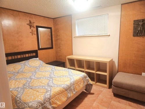 Room featuring terracotta-style floor tiles and a window with horizontal blinds - 12339 89 Street, Edmonton, AB - Indoor Photo Showing Bedroom