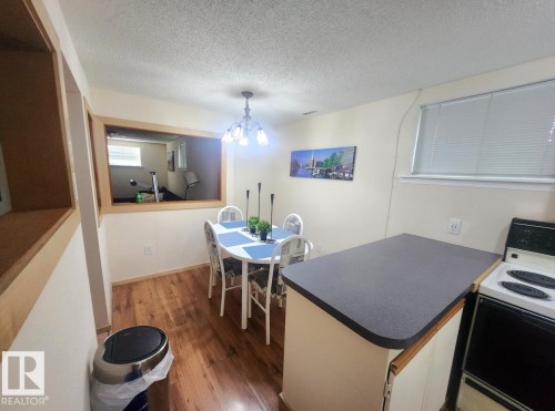 Dining area featuring wood-finish flooring, a window with blinds, and a built-in kitchen counter with a cooktop - 12339 89 Street, Edmonton, AB - Indoor