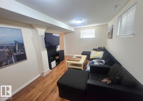 Wood-finish flooring throughout this room featuring multiple windows with blinds, a ceiling-mounted light fixture, and a built-in wall niche - 12339 89 Street, Edmonton, AB - Indoor