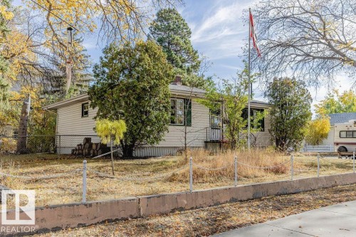Ranch-style residence featuring light-colored siding, a front porch with railing, and a mature tree on the property - 12339 89 Street, Edmonton, AB - Outdoor