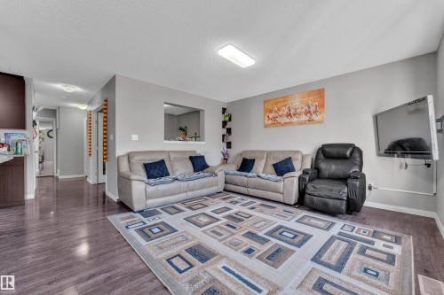 Spacious living area featuring wood-finish flooring, a neutral color palette, and a built-in wall niche - 5520 5 Avenue, Edmonton, AB - Indoor Photo Showing Living Room