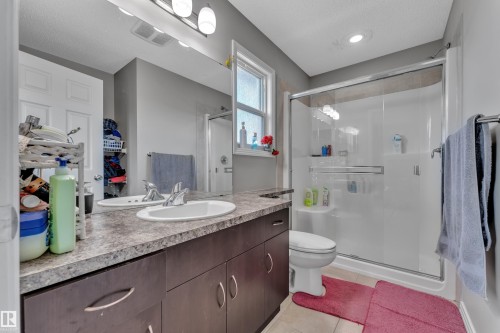 Bathroom featuring a double vanity with oval sinks, a large wall-mounted mirror, and a window - 5520 5 Avenue, Edmonton, AB - Indoor Photo Showing Bathroom