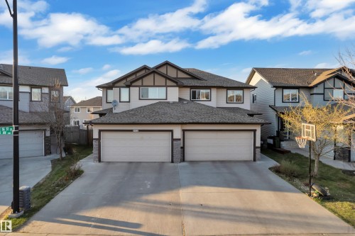 Contemporary duplex exterior featuring light-colored siding, dark trim accents, and a dual garage - 5520 5 Avenue, Edmonton, AB - Outdoor With Facade