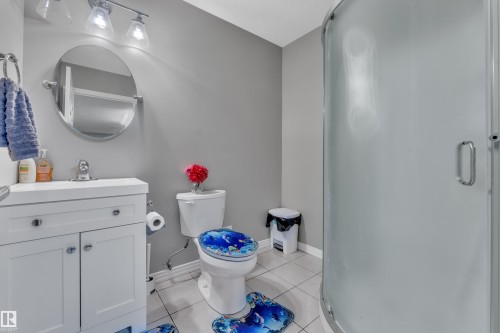 Bathroom featuring a white vanity with an integrated sink, an oval mirror, and a two-light fixture - 5520 5 Avenue, Edmonton, AB - Indoor Photo Showing Bathroom