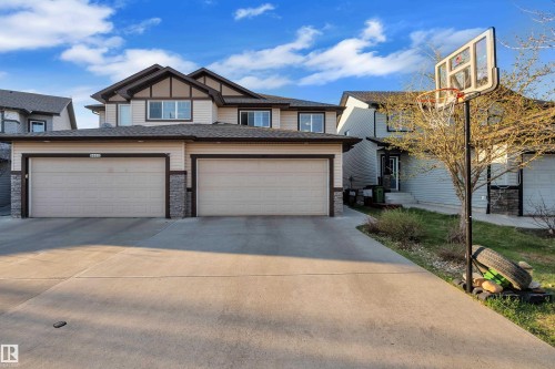 Two-story exterior featuring a two-car attached garage, stone veneer accents, and a concrete driveway - 5520 5 Avenue, Edmonton, AB - Outdoor With Facade