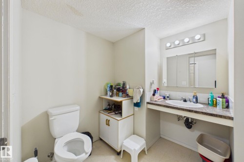 Bathroom featuring a white toilet, vanity with integrated sink, and wall-mounted medicine cabinet with mirror - 220 80A Kelloway Crescent, Red Deer, AB - Indoor Photo Showing Bathroom