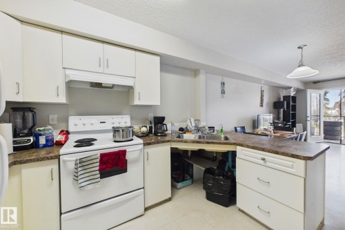 Kitchen featuring white cabinetry, laminate countertops, a built-in sink, and light flooring - 220 80A Kelloway Crescent, Red Deer, AB - Indoor Photo Showing Kitchen With Double Sink