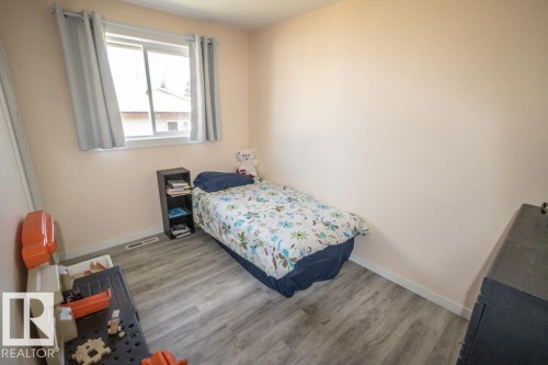 Room featuring wood-finish flooring, light-toned walls, and a window with light-filtering curtains - 4822 45 Ave, St. Paul Town, AB - Indoor Photo Showing Bedroom