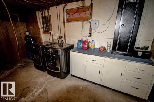Utility area featuring two front-loading laundry machines and built-in white cabinetry with a blue countertop - 4822 45 Ave, St. Paul Town, AB - Indoor Photo Showing Laundry Room